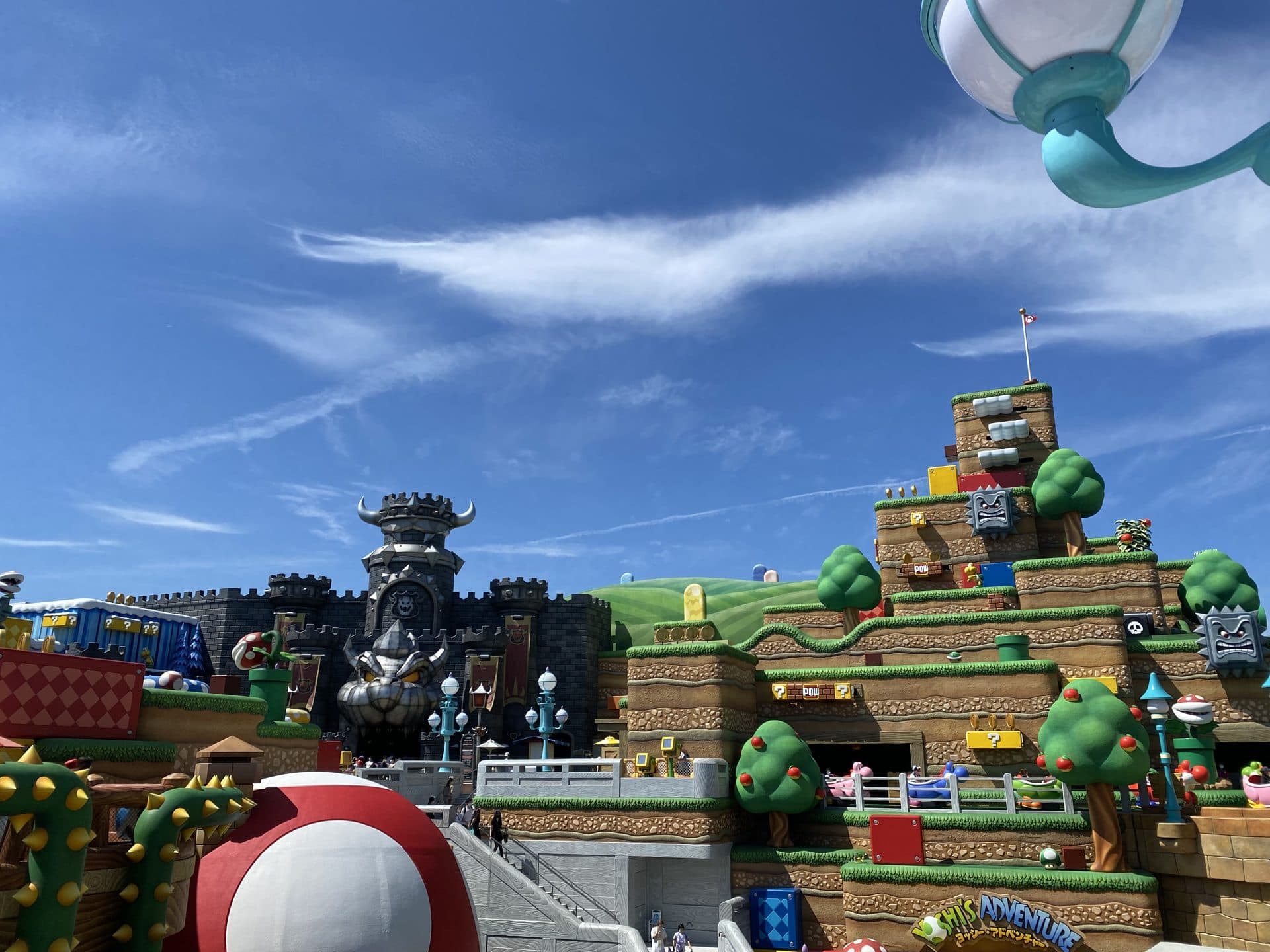 Super Nintendo World at Universal Studios Japan, with the green Mario-themed warp pipe and castle towers under a blue sky